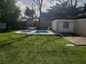 Casa com piscina aconchegante 300 m do mar في ريسيفي: ساحة بها مسبحين في العشب