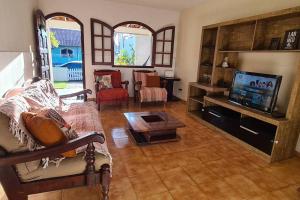 een woonkamer met een bank en een tv bij Recanto da Praia Linda in São Pedro da Aldeia