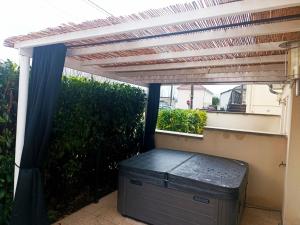a pergola on a patio with a chest under it at Cocon romantique avec jacuzzi extérieur in Rosières-près-Troyes
