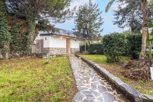 a house with a stone walkway in front of a yard at Appartamento in villa con piscina 2 in Palermo