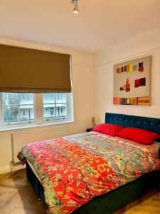 a bedroom with a bed with a colorful bedspread and a window at Bright and Airy Two Bedroom Apartment in London