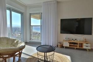 a living room with a couch and a large window at דירות קו ראשון לחוף - Apartments First line to the Beach in Qiryat Yam