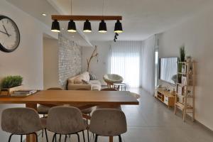un soggiorno con tavolo, sedie e orologio di דירות קו ראשון לחוף - Apartments First line to the Beach a Qiryat Yam