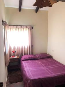 a bedroom with a purple bed and a window at Cabañas Lijeron Samaipata in Samaipata