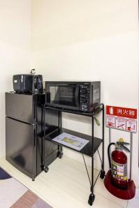 a microwave oven on a stand with a refrigerator at CROWN 海辺 in Tokyo