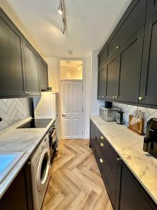 a kitchen with black cabinets and a washer at Bright and Airy Two Bedroom Apartment in London