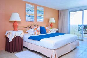 a bedroom with a large bed and a balcony at Tropical Sunset Beach Apartment Hotel in Saint James