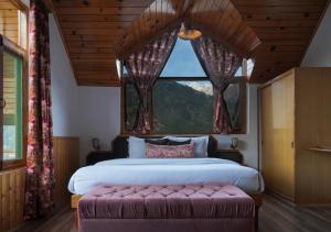 sypialnia z dużym łóżkiem i dużym oknem w obiekcie The Wooden Chalet, Manali by DBP w mieście Manāli