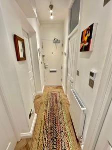 einen Flur mit einem Teppich auf dem Boden in der Unterkunft Bright and Airy Two Bedroom Apartment in London