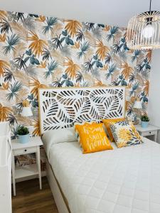 a bedroom with a white bed with a tropical wallpaper at APARTAMENTO NUEVO CÉNTRICO en PRIMERA Línea de playa con vistas al Mar, Piscina, aire acondicionado y wifi in Peñíscola