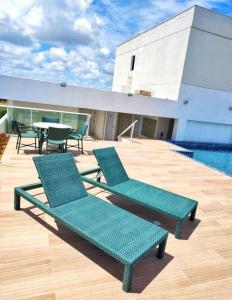 dos sillas verdes sentadas en una terraza junto a una piscina en Porto de galinhas en Porto De Galinhas