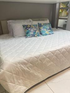 1 cama grande con sábanas y almohadas blancas en Porto de galinhas en Porto De Galinhas