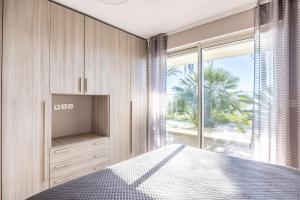 a bedroom with a bed and a large window at LE MIDI 8 by ESTATES CANNES in Cannes