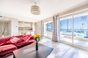 a living room with a red couch and large windows at LE MIDI 8 by ESTATES CANNES in Cannes