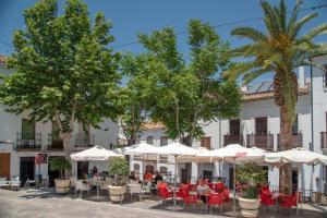 Un restaurante con mesas y sillas frente a un edificio. en La Almazara by Vintage Travel, en El Gastor