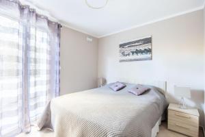 a white bedroom with a bed and a window at LE MIDI 8 by ESTATES CANNES in Cannes