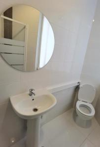 a white bathroom with a sink and a mirror at Samps Hostel in Lisbon