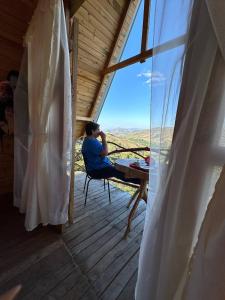 um homem sentado num alpendre a olhar pela janela em Los Nevados Ecolodge em Gigante