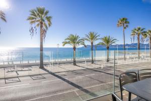 a view of a beach with palm trees and chairs at LE MIDI 8 by ESTATES CANNES in Cannes