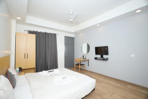 una camera con letto bianco e TV di Hotel Wedlock 51 a Gurgaon