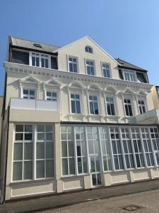 un gran edificio blanco con grandes ventanas en una calle en Seehus 8, en Norderney
