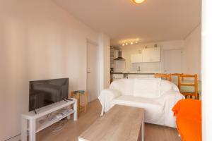 um quarto com uma cama branca e uma televisão em INNOUTHOME Apartamento Ideal Vacaciones Mediterrani em L'Ametlla de Mar