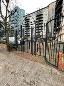 a black wrought iron gate in a city with buildings at Modern Apartment in Stratford in London
