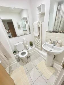 a white bathroom with a toilet and a sink at Modern Apartment in Stratford in London