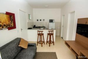 een woonkamer met een bank en een keuken bij Apart Sol Nascente in Itatiaia