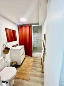 uma casa de banho com uma cortina de chuveiro vermelha e um WC. em Le Nid Douillet CENTRE VILLE em Decize