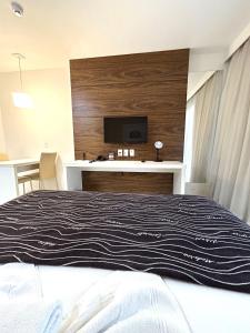 a bedroom with a bed with a tv on a wall at V1318 Lindo flat aconchegante em andar alto in Brasilia