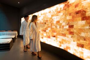 a man and woman standing next to a brick wall at Lido Palace - The Leading Hotels of the World in Riva del Garda