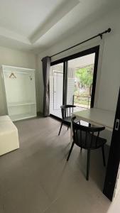ein Wohnzimmer mit einem Tisch, Stühlen und einem Fenster in der Unterkunft Ko Phangan Haad Yao Beach Hotel in Haad Tian