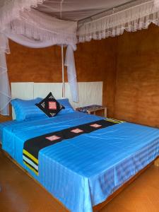 een bed in een kamer met een blauw dekbed bij Ly Quoc Tuan Homestay in Quản Bạ