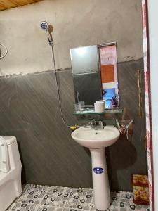 een badkamer met een wastafel en een spiegel bij Ly Quoc Tuan Homestay in Quản Bạ