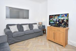 a living room with a couch and a flat screen tv at Ernest House - By Sigma Stays in Crewe