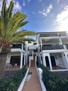 una casa blanca con una palmera delante de ella en Oasis Retreat 793 - Appartamento con piscina a Amarilla Golf, en San Miguel de Abona