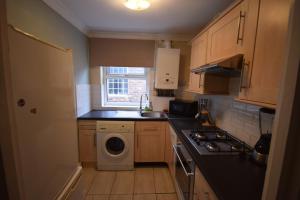 a small kitchen with a sink and a washing machine at Two Bedroom Flat St Andrews Road in London