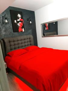 - une chambre avec un lit rouge et un miroir dans l'établissement Dream Arena Apartment, à Bacău