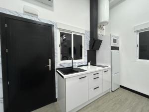 a white kitchen with a sink and a black door at Cotrades 1 En San Blas-Canillejas in Madrid