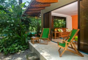 eine Terrasse mit zwei grünen Stühlen und einem Sofa in der Unterkunft Olas Verdes Hotel in Nosara