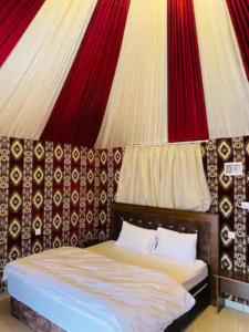 un lit dans une chambre avec un mur rouge et blanc dans l'établissement Wadi Rum Classic Camp, à Wadi Rum