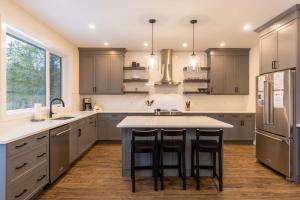 a kitchen with gray cabinets and a island with bar stools at Powder House Chalet by Fernie Central Reservations in Fernie