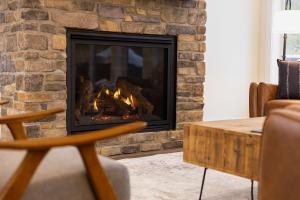 a fireplace in a living room with a stone wall at Powder House Chalet by Fernie Central Reservations in Fernie