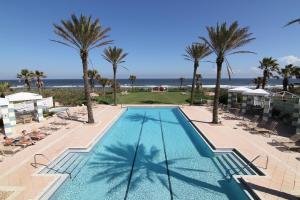 einen Pool mit Palmen und dem Meer in der Unterkunft Come stroll along the beach and enjoy shared resort style amenities! in Palm Coast