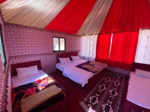 Habitación con 2 camas y techo rojo. en Calm Camp en Wadi Rum