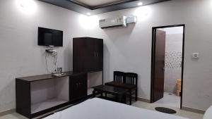 um quarto com uma secretária, uma televisão e uma cadeira em Tiger Guest House & Restaurant em Sawai Madhopur