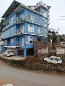 two cars parked in front of a blue building at Snowline Homestay in Kīar