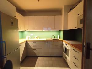 una cocina con armarios blancos y paredes verdes en Apartament Lux Corner Park Warsaw, en Pruszków