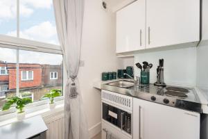 uma cozinha branca com um lavatório e uma janela em Small and Trendy studio 3B em Londres